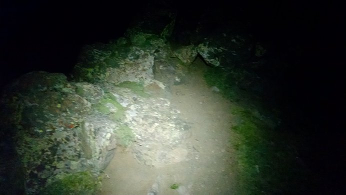A circle of light from a headlamp illuminates a bit of the trail on the trail to Wetterhorn Peak