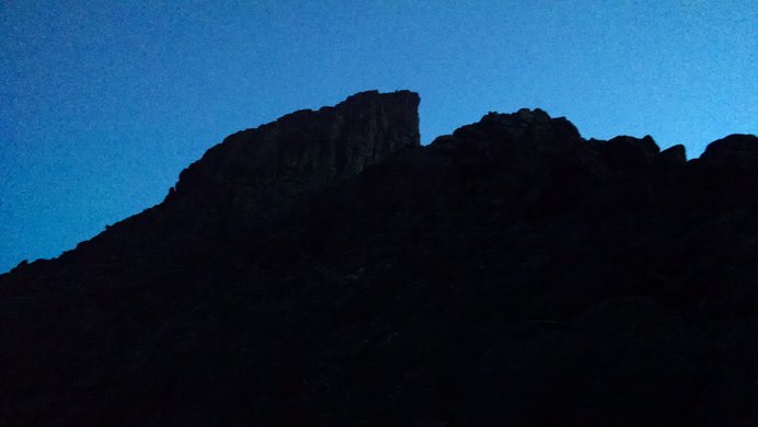 Wetterhorn Peak's ridgeline (with the Prow on the left) silhouetted with a faint blue sky behind