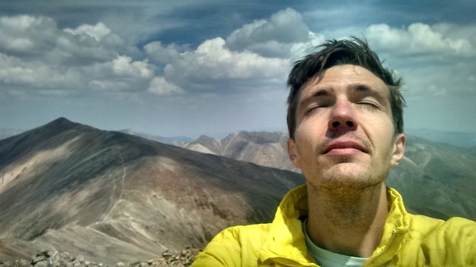 I close my eyes as I soak in the sun on Sunshine Peak, with Redcloud behind me