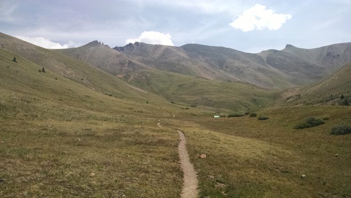A panoramic view up into the grassy basin below Redcloud Peak