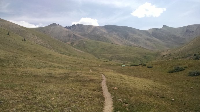 A panoramic view up into the grassy basin below Redcloud Peak